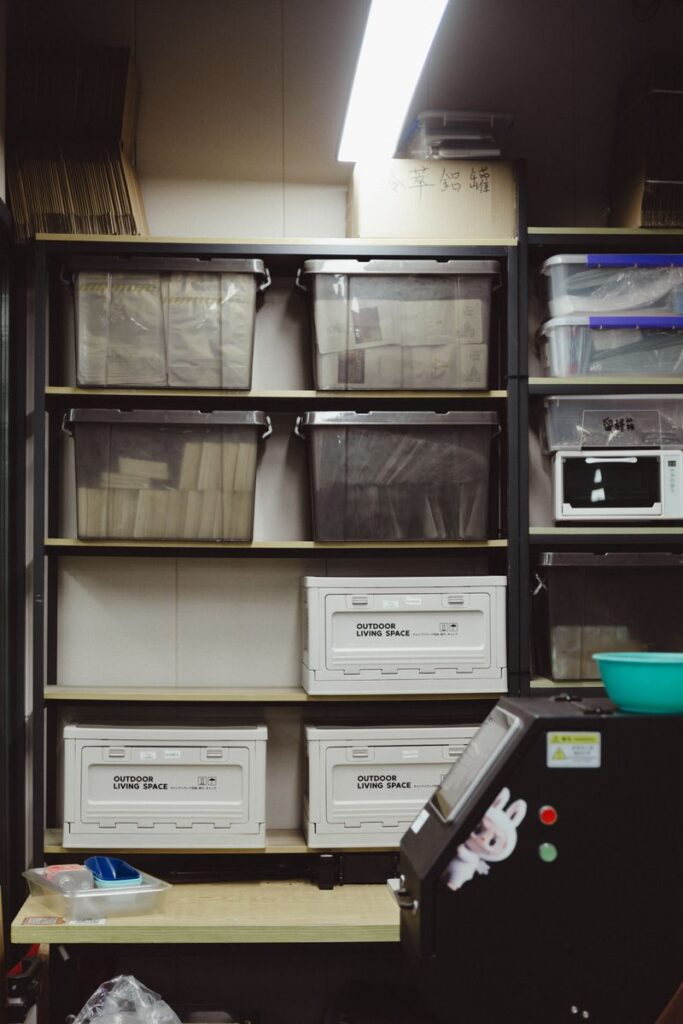 pexels-photo-36946571-36946571 A neatly arranged storage room with shelves filled with plastic containers and boxes.